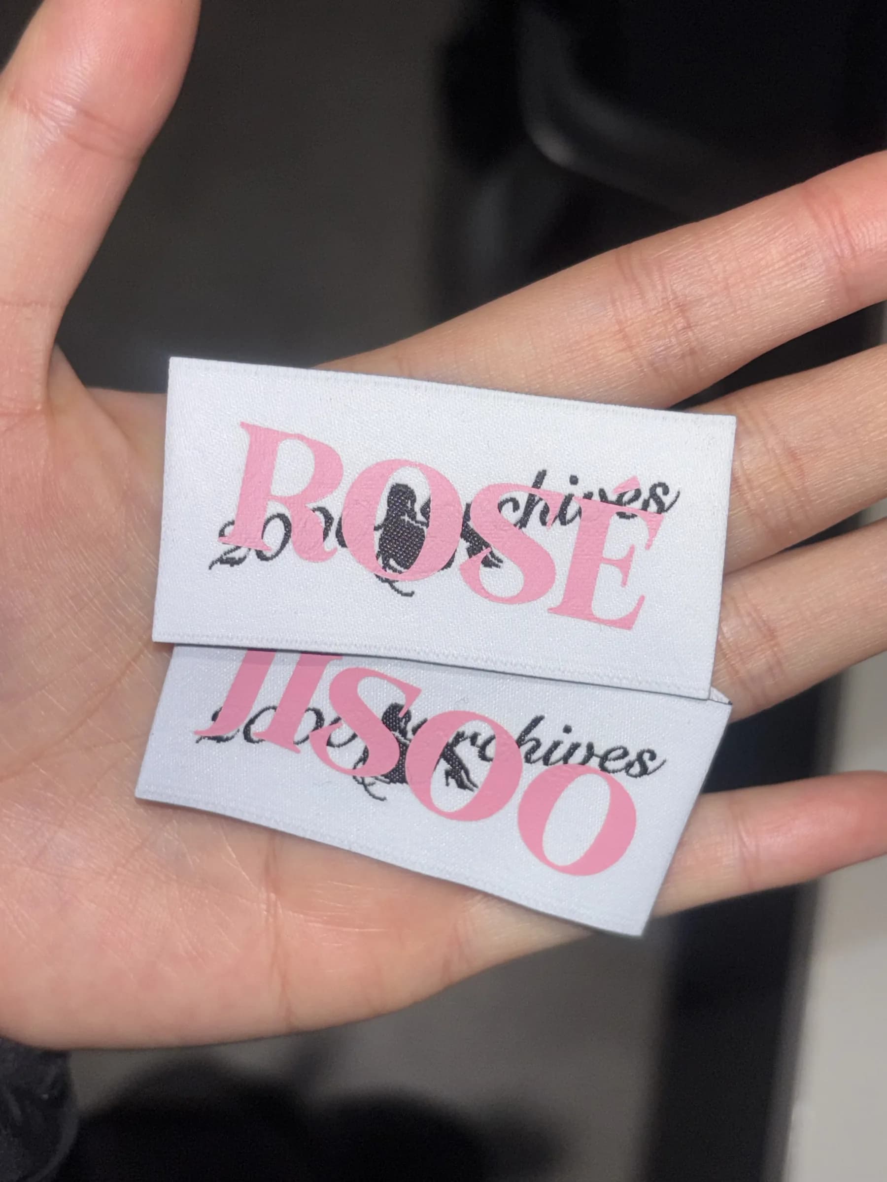 Per-member woven labels — ROSÉ and JISOO — for the tour pieces