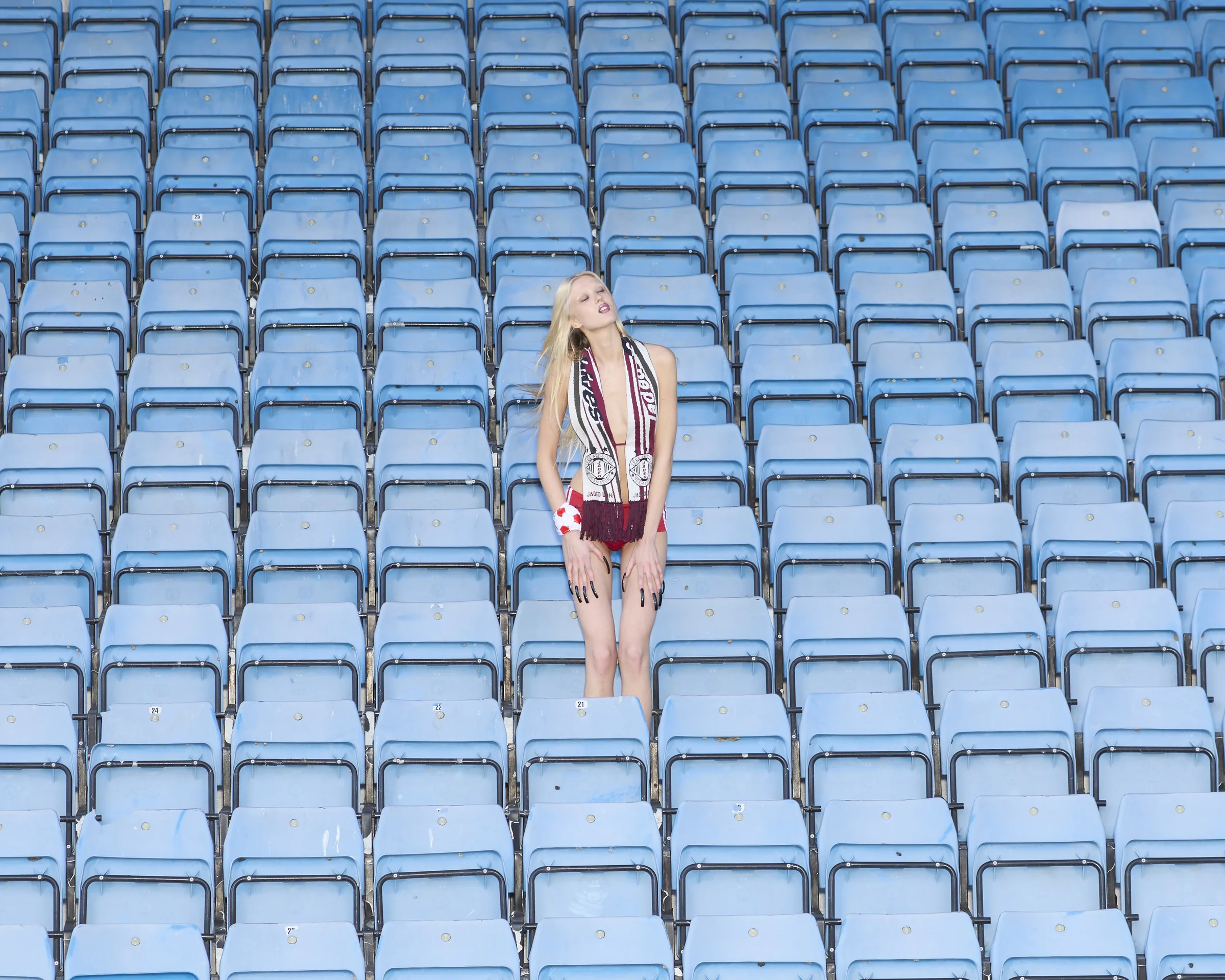 Sport Couture — a lone figure in a sea of blue stadium seats